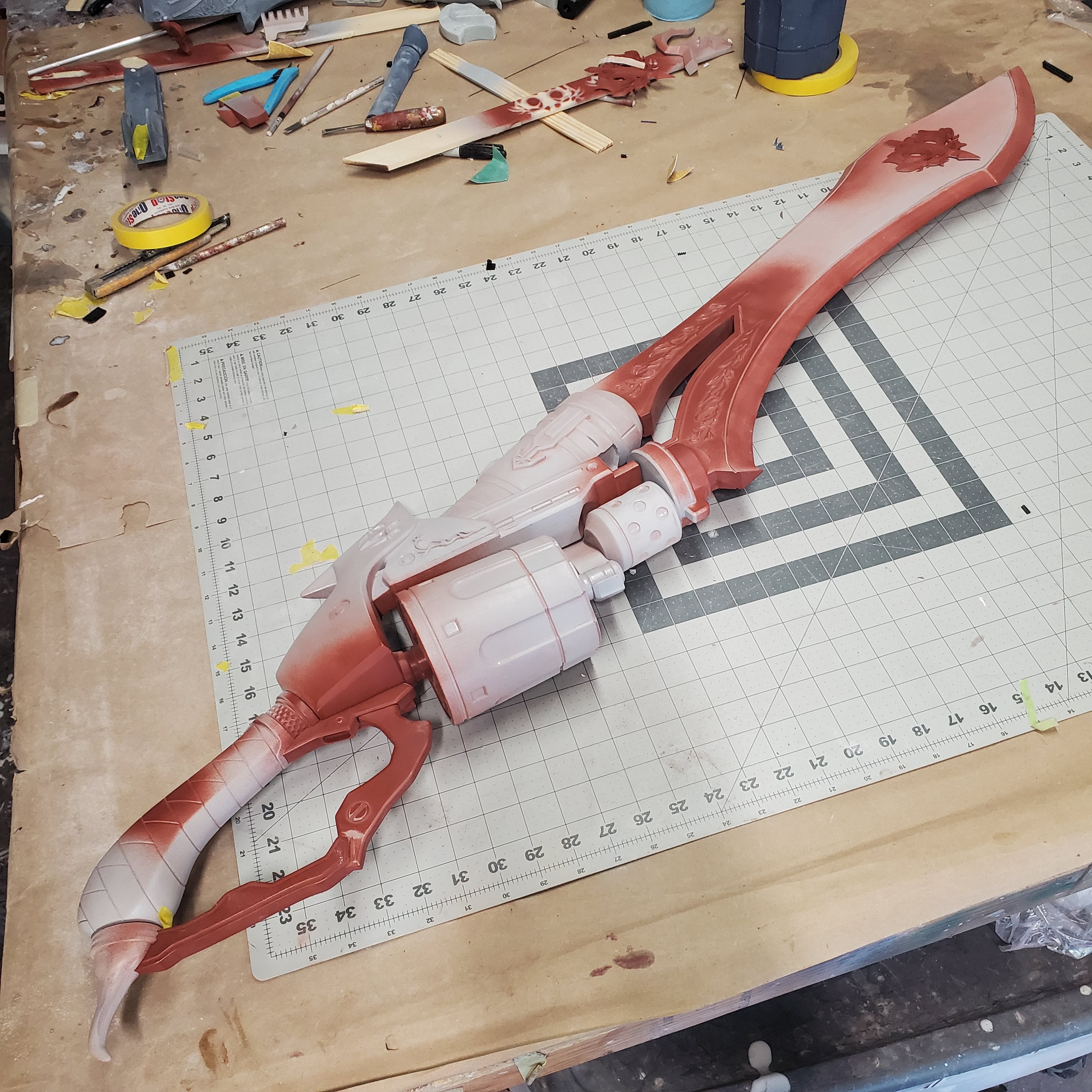 Red and white mechanical arm model on a cutting mat with tools around