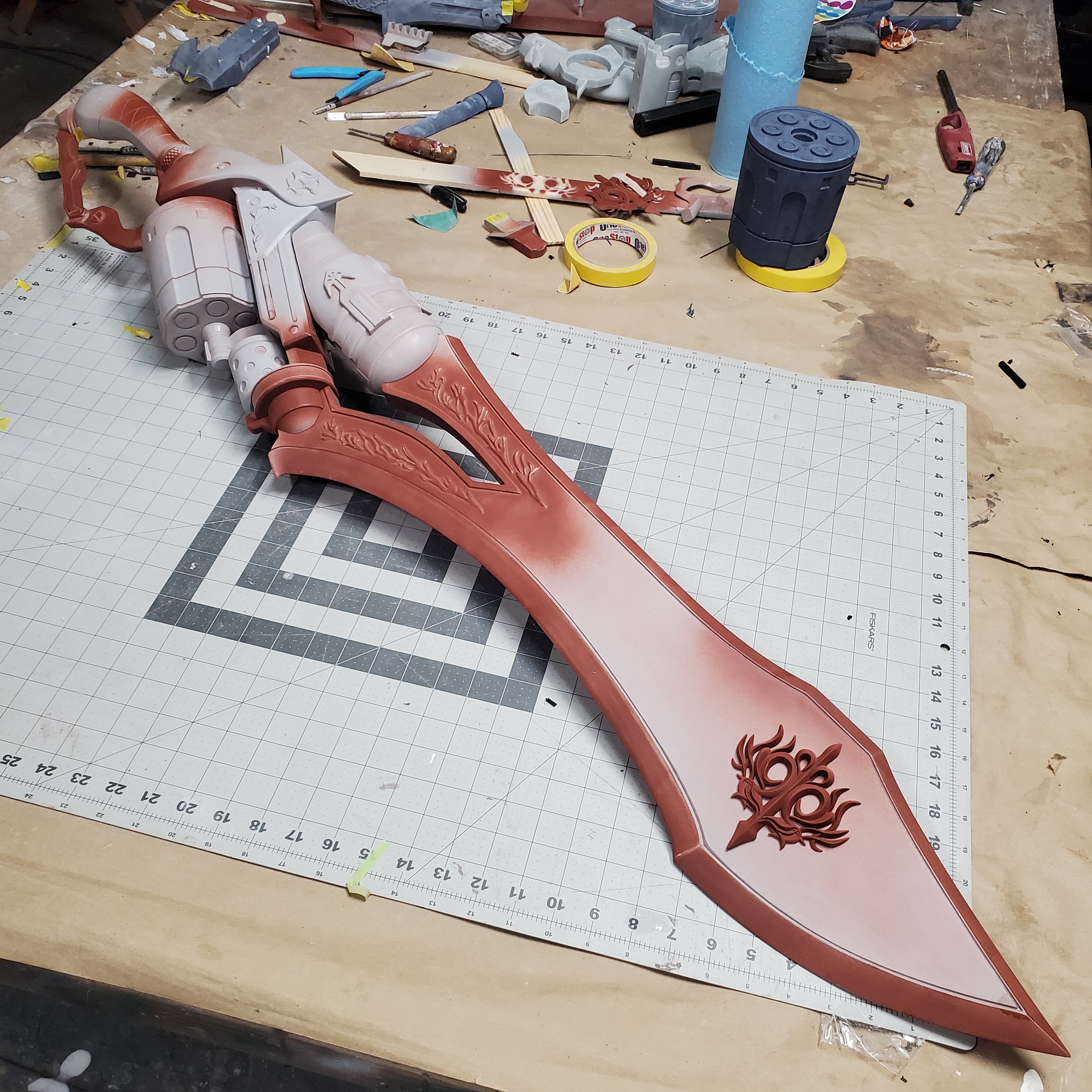 Large red weapon prop on a cutting mat with tools in the background