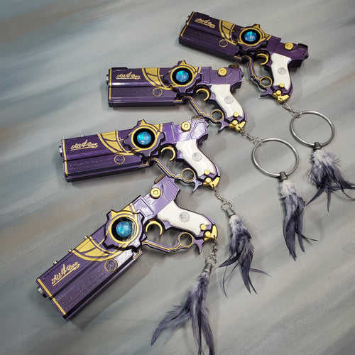 Purple and gold keychain with blue gemstones on a gray background