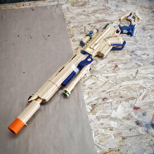 Toy gun with beige and blue design on a wooden surface