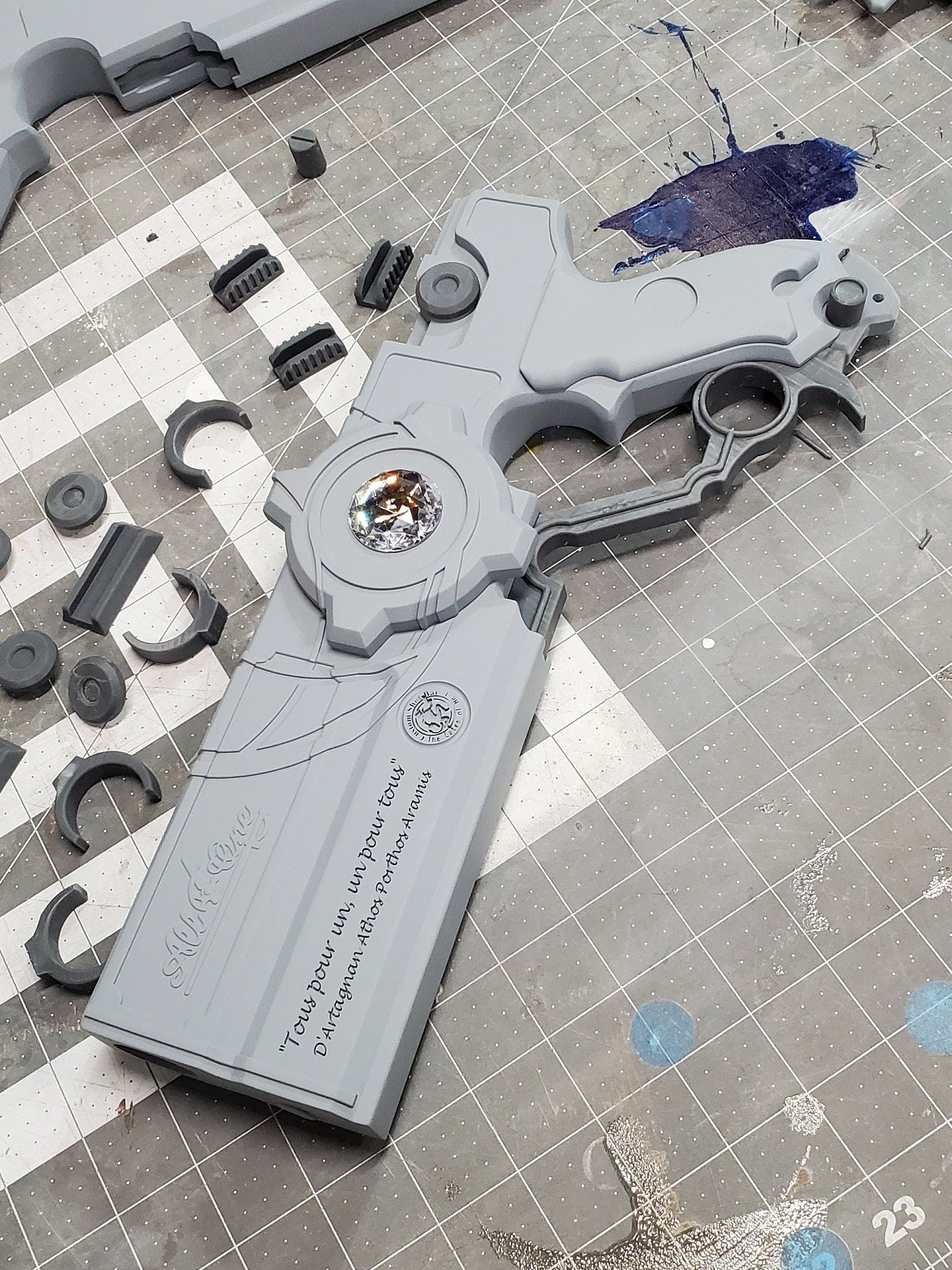 Gray fidget spinner on a checkered surface with scattered parts